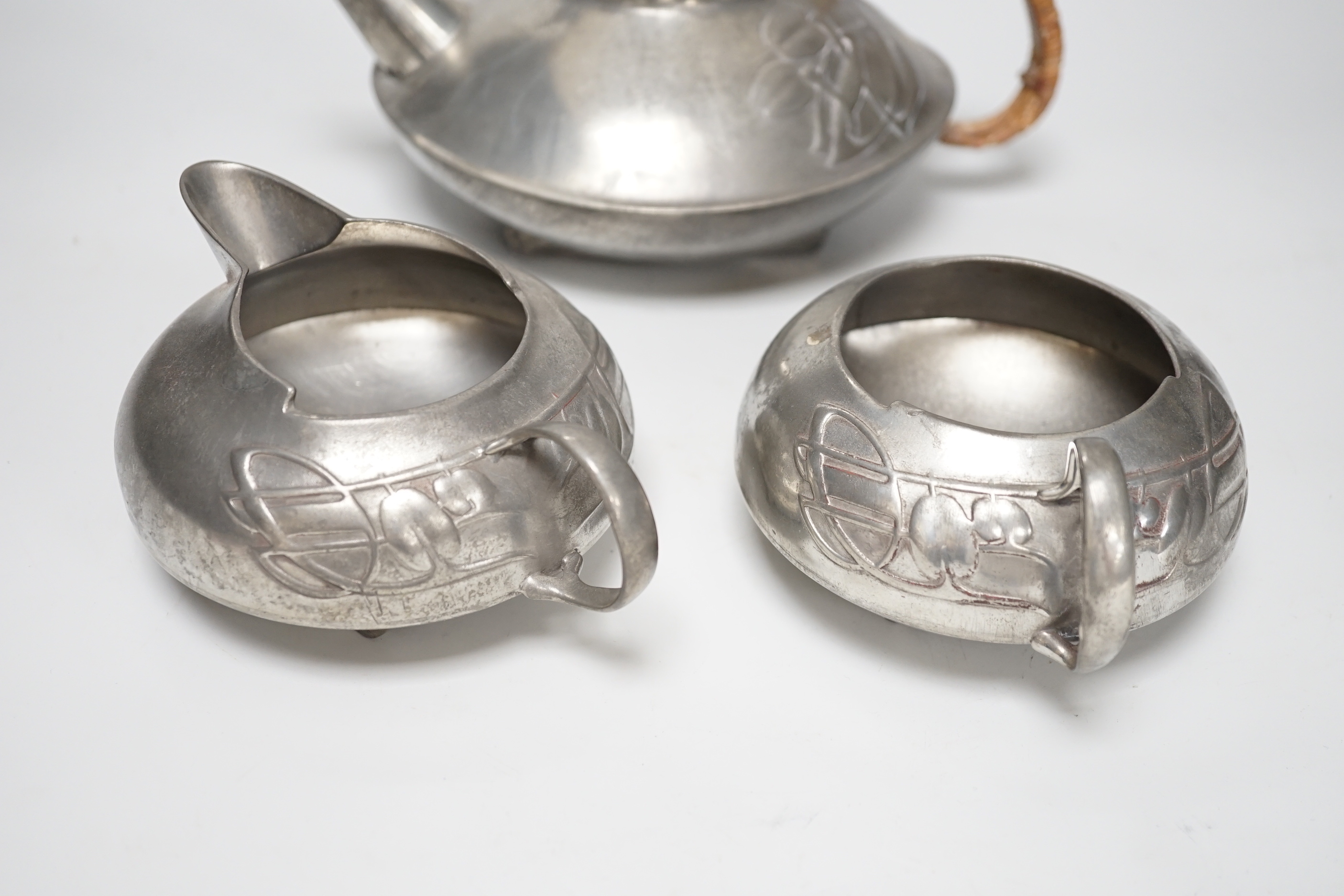 Art Nouveau Archibald Knox for Liberty, Tudric pewter three piece tea set, the teapot with woven handle, each stamped 0231 to the base, the largest 23cm wide